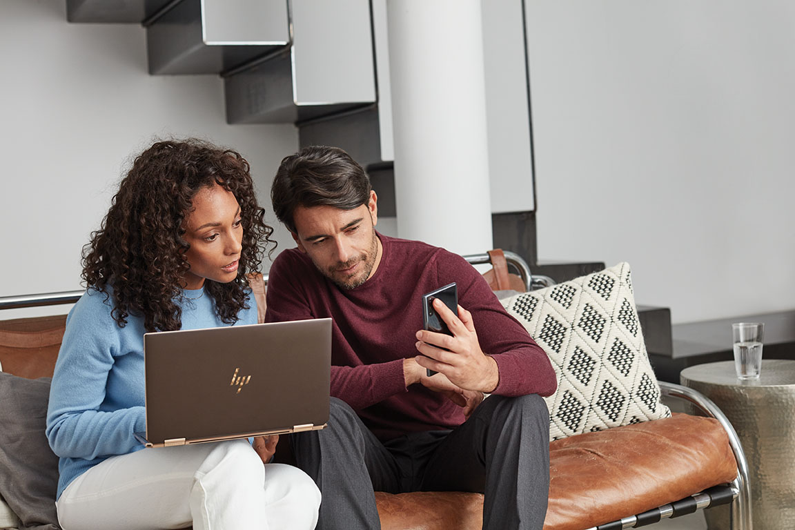 Adults inside home working on laptop and phone. Back to school. HP Spectre X360