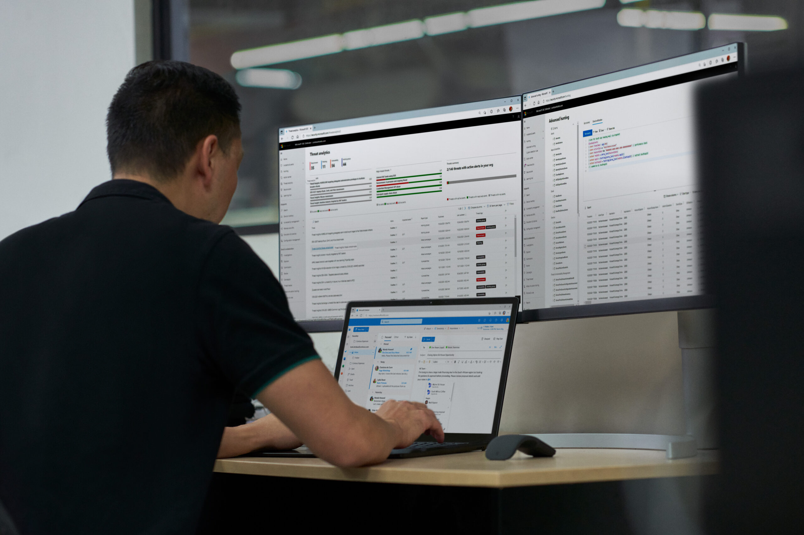 Photo of a male IT pro looking at an admin center on three displays.