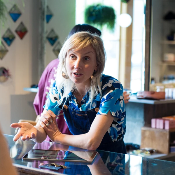A woman in overalls talking to a customer