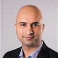 a man wearing a suit and tie smiling at the camera