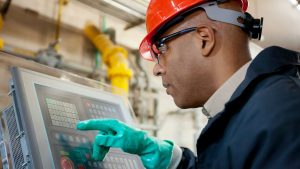 A man in protective equipment working on a machine.
