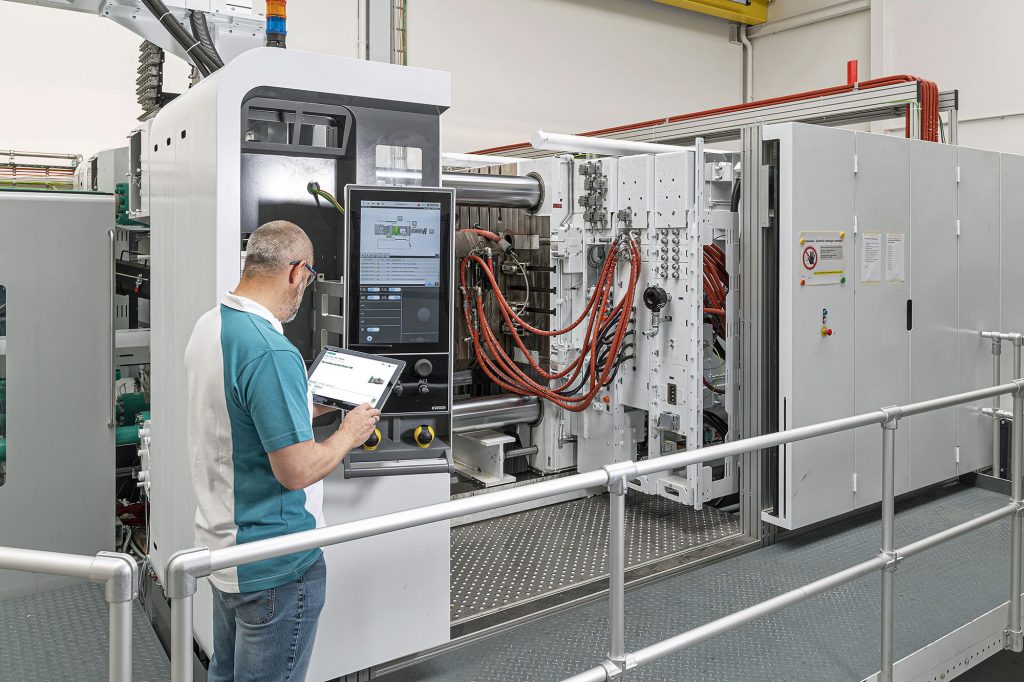 Man working in factory using a device to perform maintenance on machine