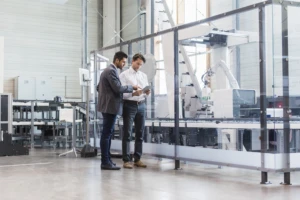 Two businessmen with tablet talking in modern factory