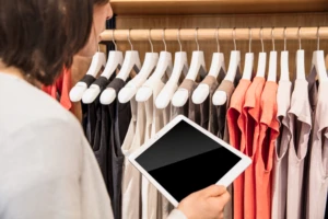 person in a clothing store looking at a tablet