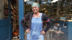 Female entrepreneur standing outside her grocery store business.