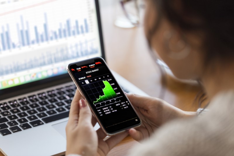 Woman looking at smartphone and PC displaying financial data Here's the alt text for the body copy image: Smartphone with financial data displayed with persona image in corner