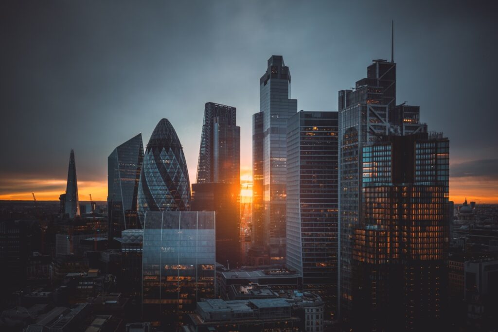 Aerial panoramic view of cityscape skyline with metropole financial district modern skyscrapers during sunrise with illuminated buildings and cloudy sky in London, UK