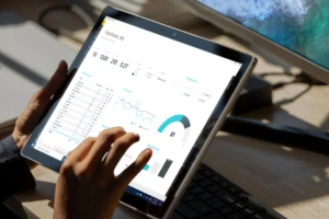 A woman's hand interacting with a data and analytics dashboard on a touchscreen laptop..