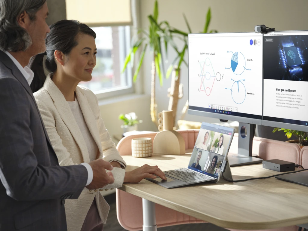 a man and a woman standing in front of a laptop
