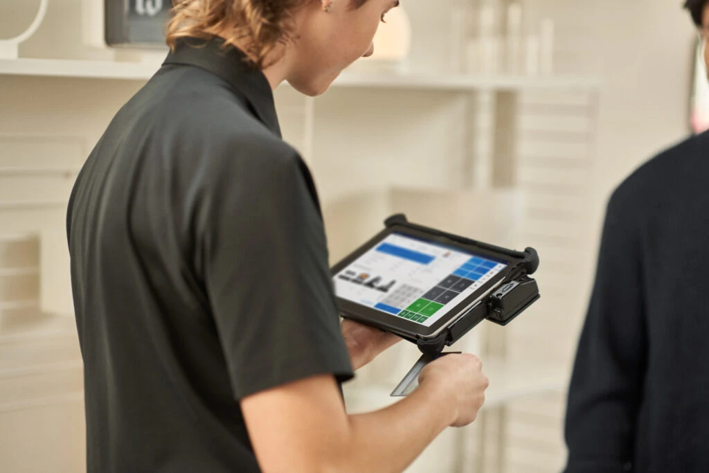 Retail customer picking up order in-store, paying with a credit card and checking out with customer service who‘s using a tablet for point-of-sale (POS).