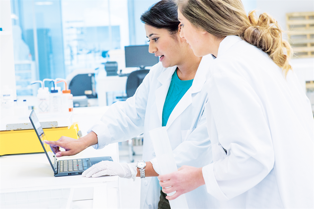 two healthcare workers examining something on a laptop