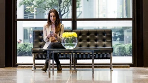 woman sitting on a black couch using her phone
