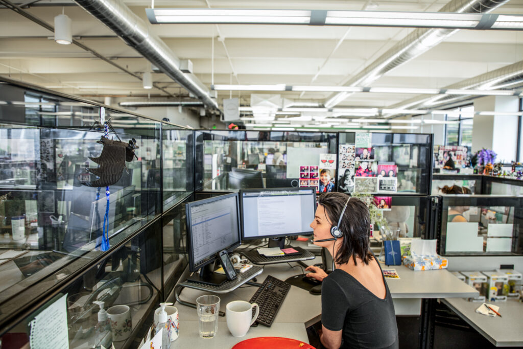 A woman sitting at a desk with a headset and computer screens