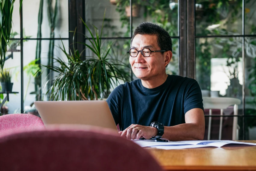 Decorative, a person smiling while working on a laptop. 