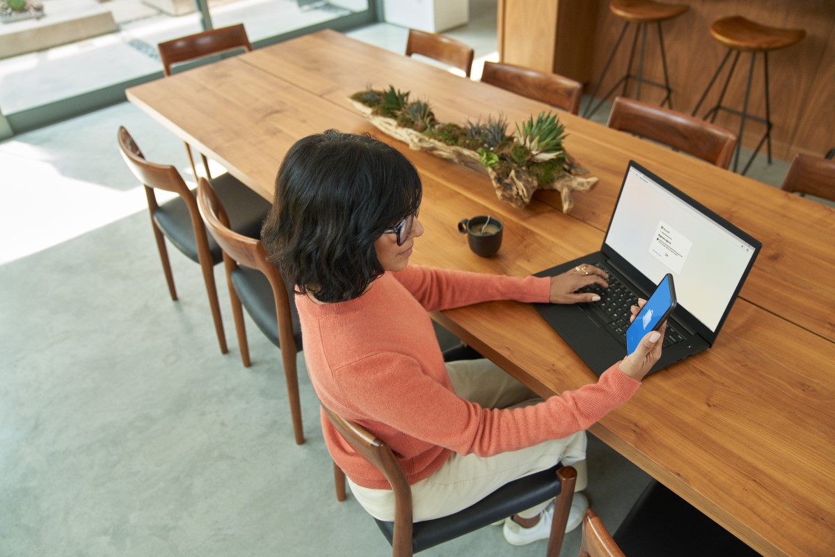 Business decision maker using mobile phone to complete multi-factor authentication to prepare to work from home.