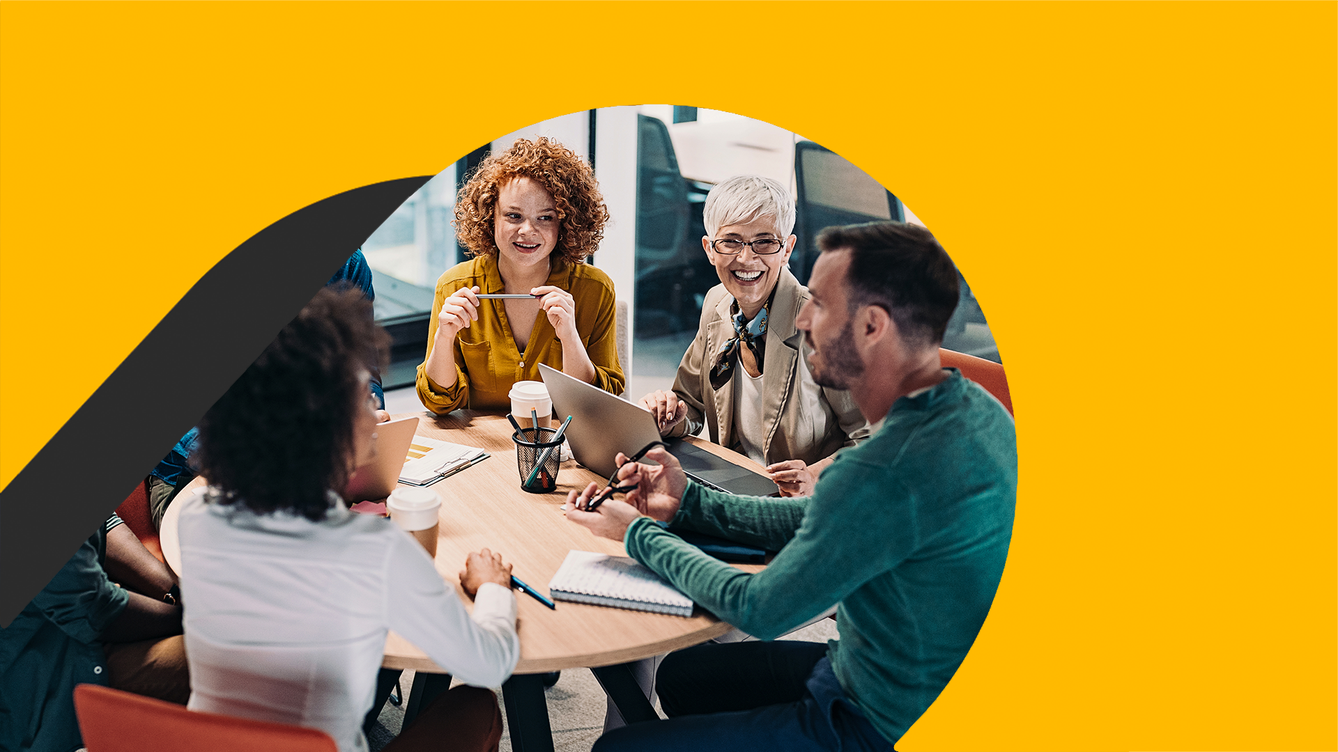 Group of business people having a meeting at a round conference table in a creative office.