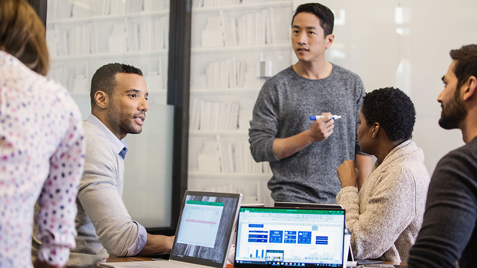 A group of colleagues have a discussion in front of a whiteboard