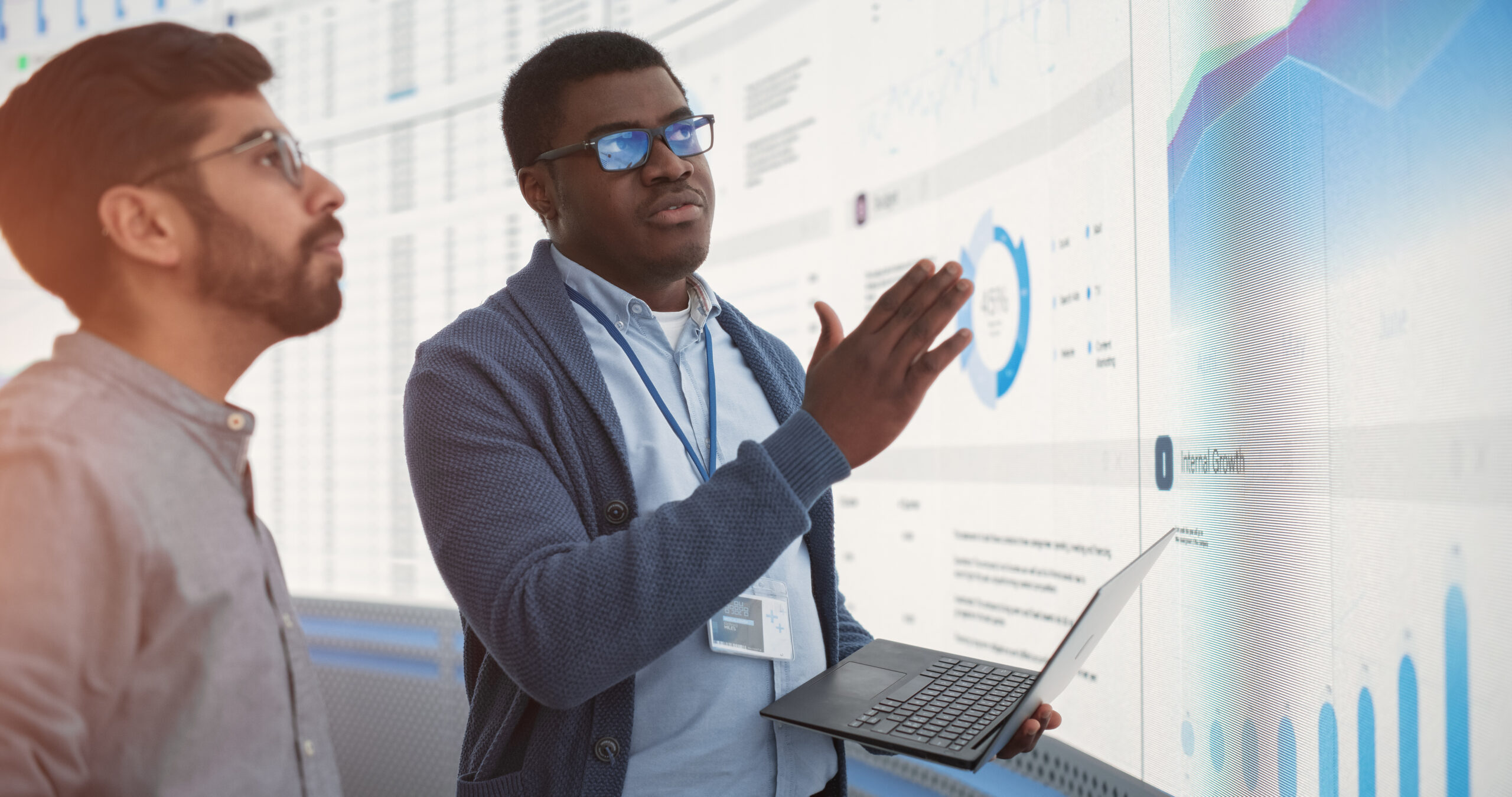 Two men looking at computer screen with charts