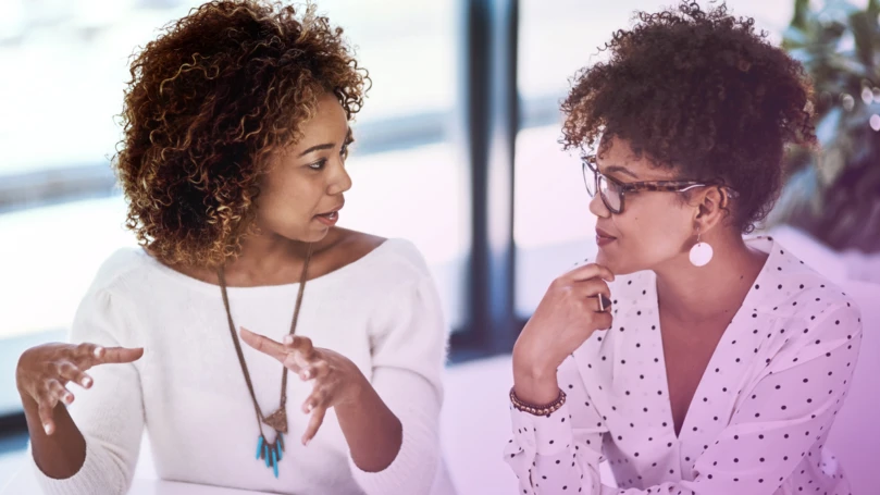 Two people in discussion, working in a modern office.