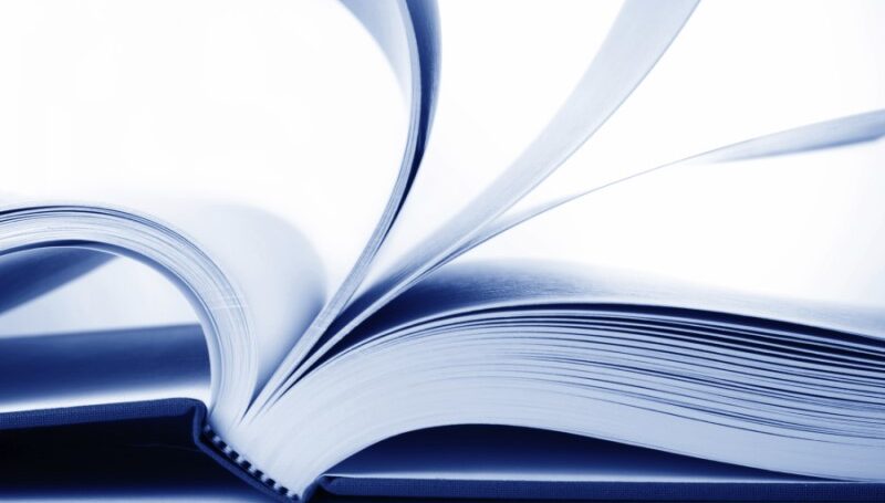 Close-up of an open book with flipping pages. Blue-toned.