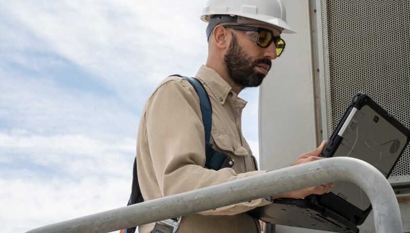 Field engineer viewing data on a laptop after inspecting turbines on a wind farm.