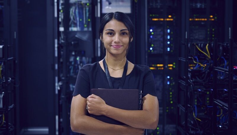 Woman in a server room holding a notebook