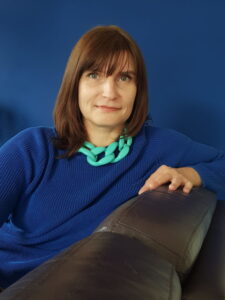 Irina Chemerys relaxes on a chair wearing a sweater and chunky necklace.