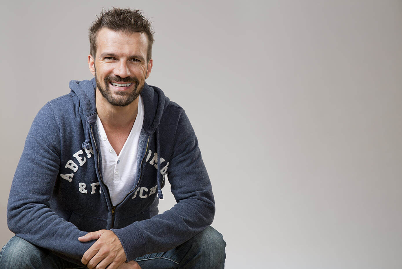 Thiede smiles as he crouches looking at the camera in a professional photo.