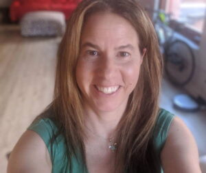 Allison Koch looks at the camera and smiles from a home office.