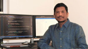 Pavan Jayavarapu sits at his desk and smiles at the camera.