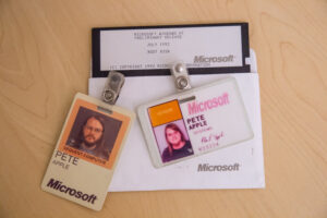 Collection of old two early Microsoft badges and a Windows boot disk from when Apple first started working at Microsoft.