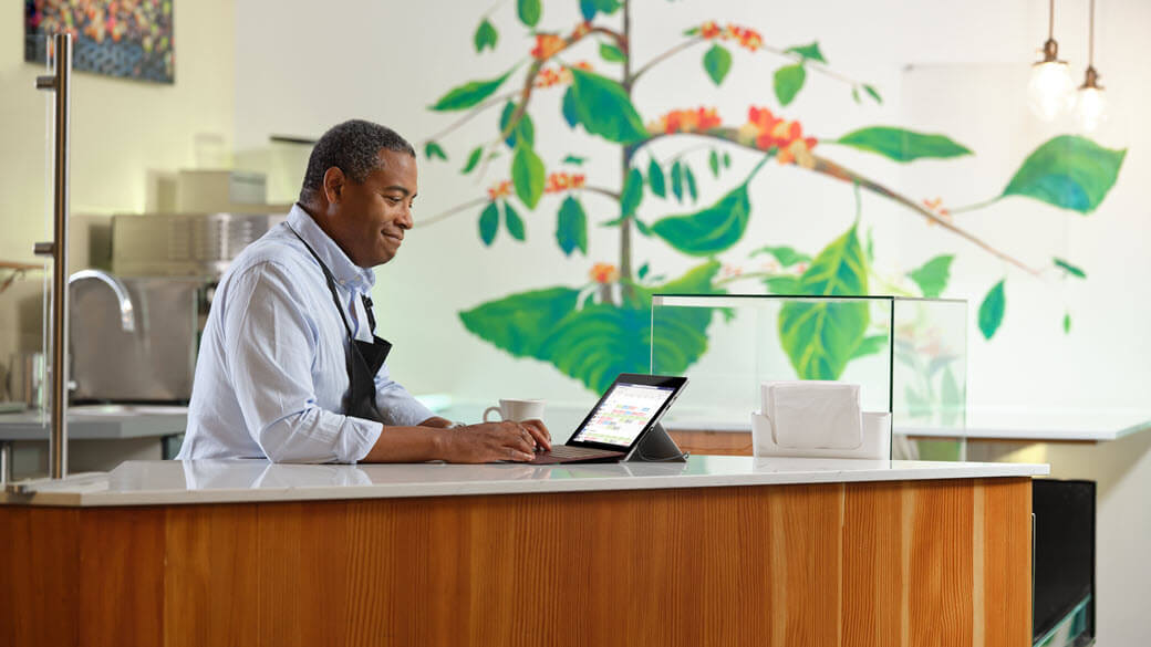 A person working at a desk in a kitchen uses Yammer to check in on activities at their company.