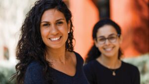 Two female employees face the camera smiling.