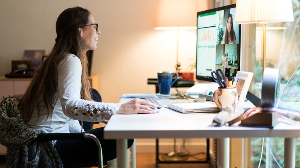A woman seated at a desk using a computer and looking at the screen.
