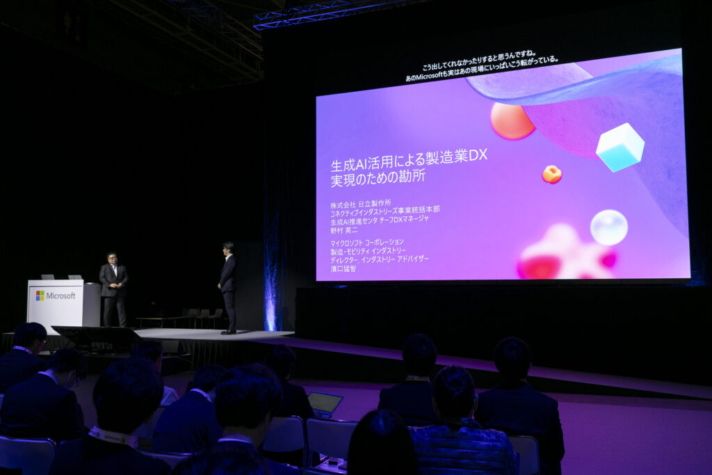 A man standing on stage with a large screen